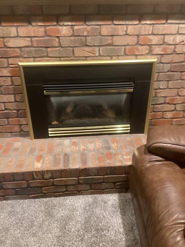 Responded to service call for dual fireplace system with non-functional upstairs unit. Inspected 9-year-old gas fireplace insert with brass surround in upstairs family room that failed to ignite. Also evaluated downstairs gas fireplace insert with black metal frame in white brick surround per customer request. Documented both units with photos showing fireplace condition, insert configuration, and surrounding installations for diagnostic assessment and repair recommendations.