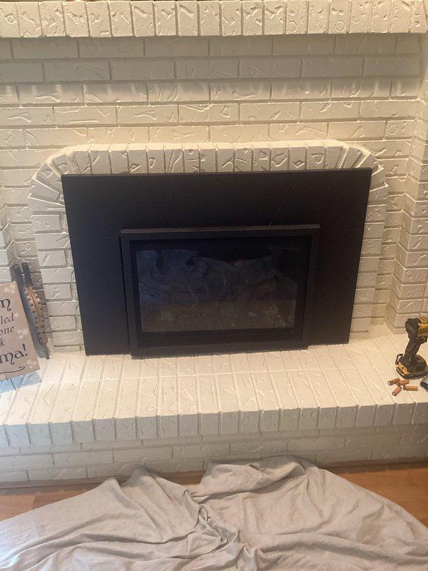 Responded to service call for dual fireplace system with non-functional upstairs unit. Inspected 9-year-old gas fireplace insert with brass surround in upstairs family room that failed to ignite. Also evaluated downstairs gas fireplace insert with black metal frame in white brick surround per customer request. Documented both units with photos showing fireplace condition, insert configuration, and surrounding installations for diagnostic assessment and repair recommendations.