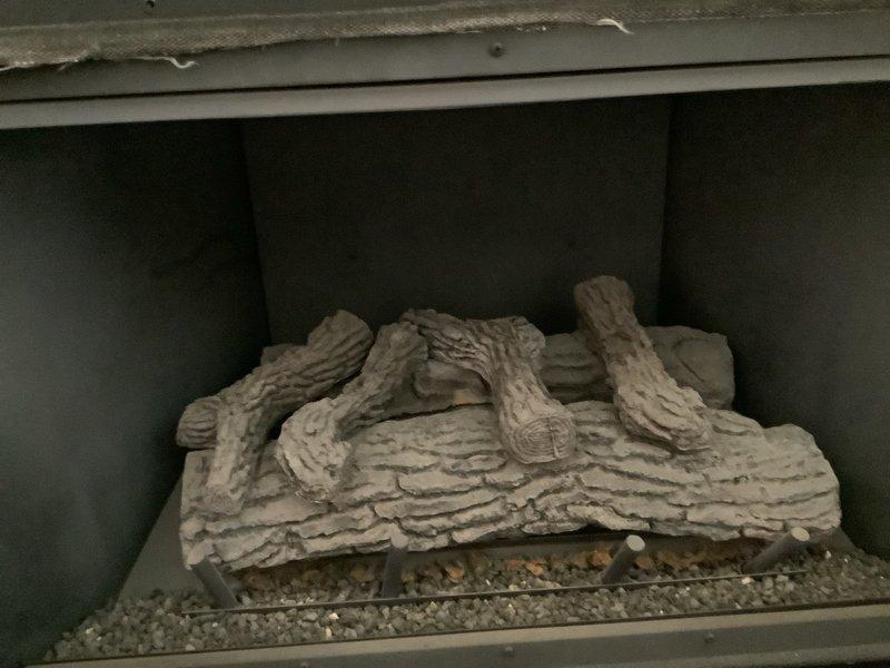 Installed fireplace blower kit on gas fireplace insert with decorative ceramic log set and glass front. Completed system makeover, ensuring proper ventilation through existing louvers and verifying blower operation with heat distribution system. Unit tested and confirmed operational with all components functioning as designed.