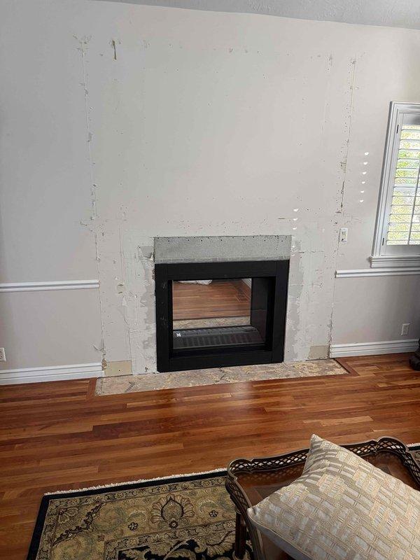 Completed QA visit for fireplace installation to verify clearance specifications for mantel and surround materials. Inspected cement board substrate installation around black metal fireplace insert and documented current construction phase with photos. Reviewed proper clearance requirements with homeowner to ensure compliance with manufacturer specifications before final finishing materials are applied.