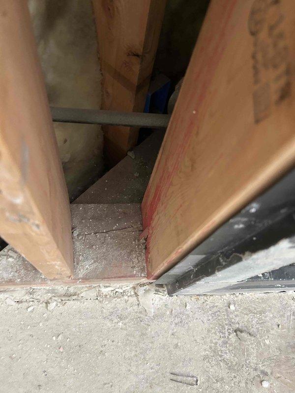 Performed an on-site assessment of the fireplace installation for estimating purposes at a construction-stage project. Inspected the unfinished framing cavity, noting insulated line routing between wall studs and dusty, unfinished concrete slab conditions, and documented the gas shutoff key valve with escutcheon plate at the wall. Photographed all areas to support the estimate and confirm rough-in conditions before proceeding.
