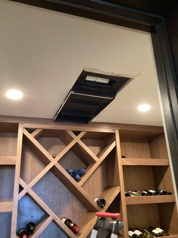 Responded to a call for a wall-mounted ductless mini split in the garage that was running but not cooling its ducted wine room, with a loud beeping alarm and the room holding at 72°F. Inspected the wine room's ceiling-mounted supply unit and surrounding drywall opening, which showed active renovation debris and rough, torn drywall edges around the cutout. Documented existing conditions and system status with photos for further diagnostics and repair planning.