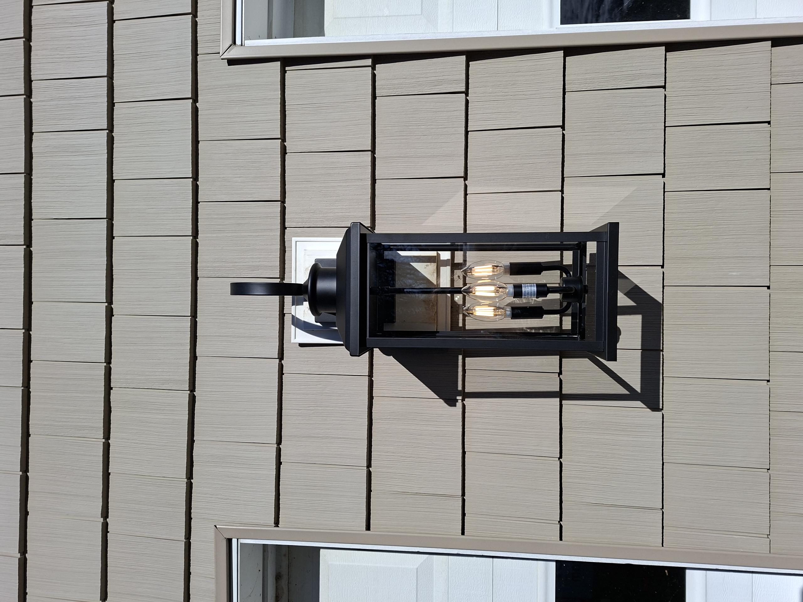 Replace customer supplied fixture between two garage doors on the side of the home.