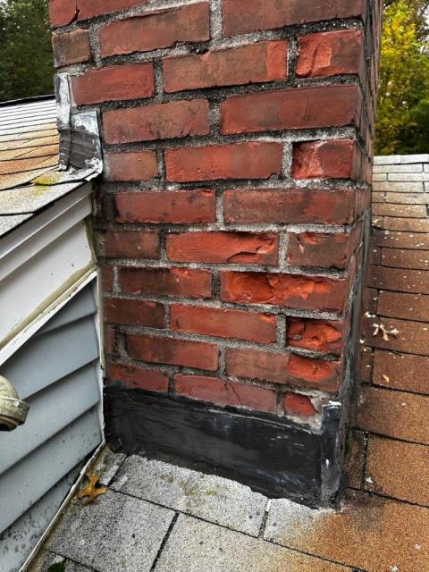 Chimney with spalled and popped brick due to water penetration, flashing was previously tarred over.  Rebuilt with custom aged looking brick, with new proper roof flashing.