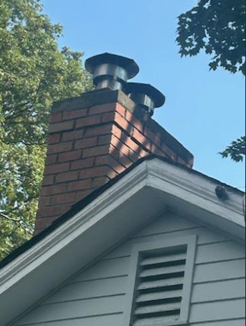 The top of the chimney has structural damage, open joints, and a fractured crown, likely worsened by a previous cover-up, leading to trapped moisture and accelerated deterioration. To stop further damage, the entire chimney top needs to be rebuilt down to the roofline with new materials and proper flashing.