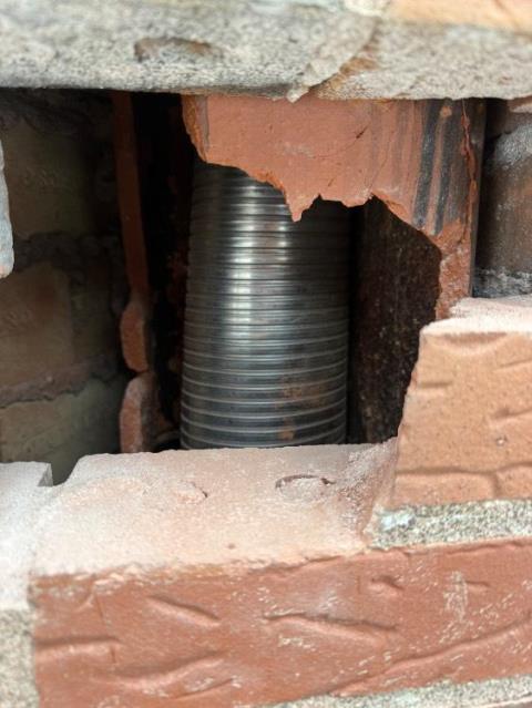 In Manchester, CT, the flue tiles serving the heating system were in poor condition, with two severe offsets located near the fireplace area. In order to properly reline the flue and create a gas-tight venting system, small, surgical masonry breaches were made to remove interior masonry obstructions.