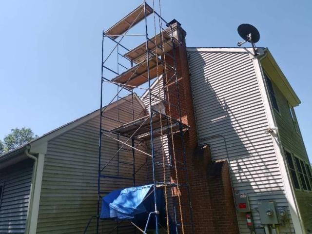 In Manchester, CT, doing a roof-up chimney rebuild due to extensive water damage and freeze/thaw deterioration. New brick, mortar, lead flashing, a cement crown, and a stainless steel multi-flue cap.