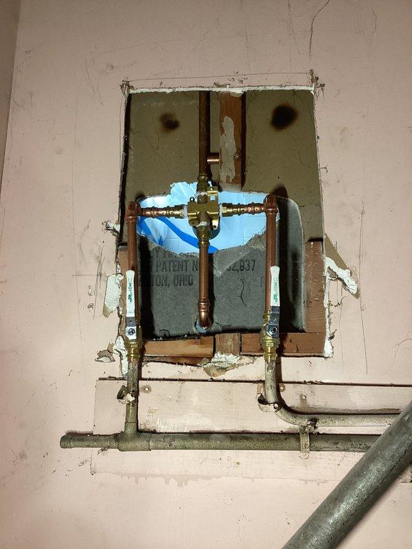 Successfully replaced existing shower valve in bathroom to restore proper functionality. Opened wall access point to remove old valve assembly and installed new chrome single-handle shower control with matching bathtub spout. Verified proper operation after installation with no leaks present.