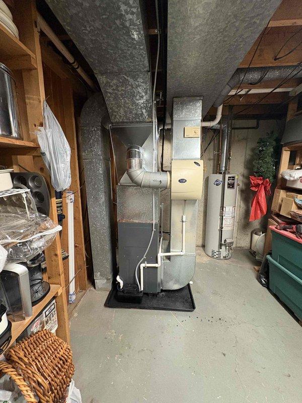 Successfully completed installation of a new Carrier furnace system in the basement utility room. Unit was properly mounted on a platform with all required ductwork connections, PVC ventilation piping, and electrical components installed according to manufacturer specifications.