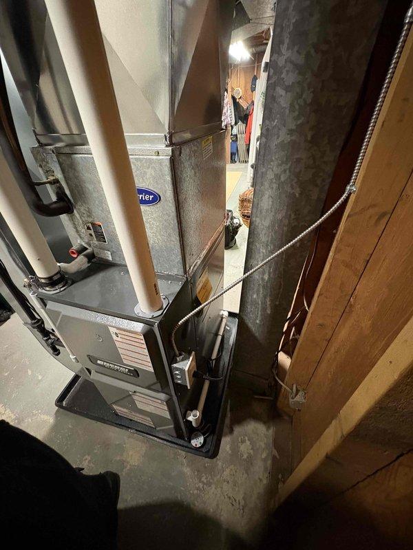 Successfully completed installation of a new Carrier furnace system in the basement utility room. Unit was properly mounted on a platform with all required ductwork connections, PVC ventilation piping, and electrical components installed according to manufacturer specifications.