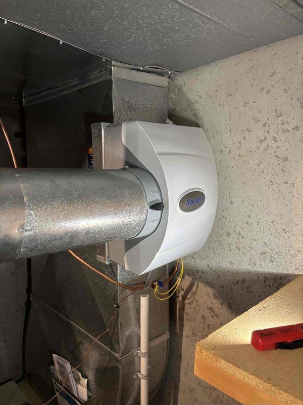 Responded to service call for a leaking Aprilaire humidifier installed on ductwork of a 20+ year old HVAC system. Diagnosed water leak originating from the aging humidifier unit, which had deteriorated components but was still allowing the heating and cooling system to function properly. Recommended replacement due to age and condition of the unit.