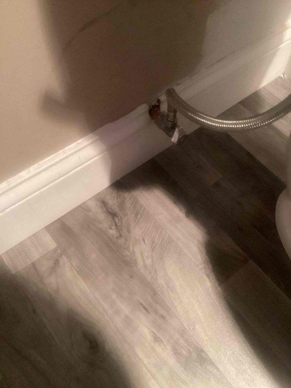 Responded to plumbing leak call at customer's residence. Located water leak at supply line connection point where it enters through the baseboard. Replaced damaged stainless steel braided supply line and properly sealed the wall penetration to prevent future leakage. Verified repair with pressure test ensuring complete resolution of the issue.