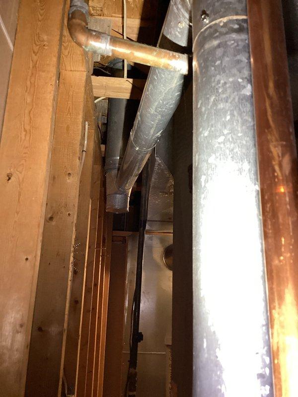Performed inspection of 25-year-old water heater failing to provide adequate hot water for household of five. Examined installation area and existing plumbing connections (documented with photos of pipe infrastructure and structural cavity). Provided customer with replacement options and complete estimate for new water heater installation.