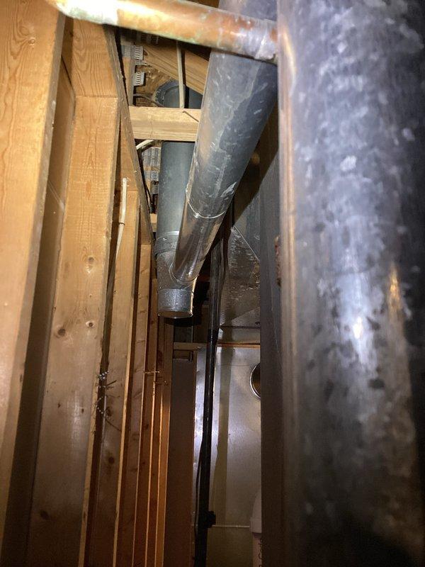 Performed inspection of 25-year-old water heater failing to provide adequate hot water for household of five. Examined installation area and existing plumbing connections (documented with photos of pipe infrastructure and structural cavity). Provided customer with replacement options and complete estimate for new water heater installation.