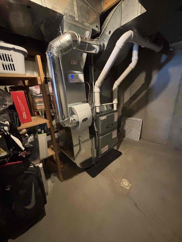 Successfully completed furnace installation in basement utility room. Installed new two-stage furnace unit with proper ductwork connections, including metallic elbow air ducts and PVC condensate drainage system. System includes an integrated whole-house humidifier mounted on the furnace side panel.