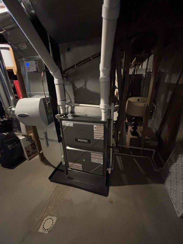 Successfully completed furnace installation in basement utility room. Installed new two-stage furnace unit with proper ductwork connections, including metallic elbow air ducts and PVC condensate drainage system. System includes an integrated whole-house humidifier mounted on the furnace side panel.
