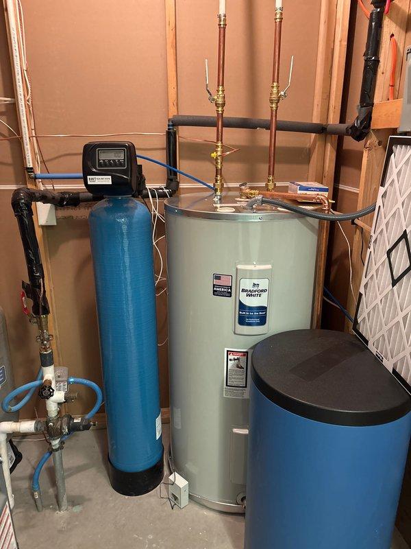 Successfully completed comprehensive HVAC system upgrade, installing new furnace, AC unit, and water heater. The installation included proper mounting of the outdoor condenser unit on a concrete pad with appropriate refrigerant line connections, and complete setup of the water heating system with associated filtration components including a water softener and brine tank, all properly plumbed with copper piping and brass valves.