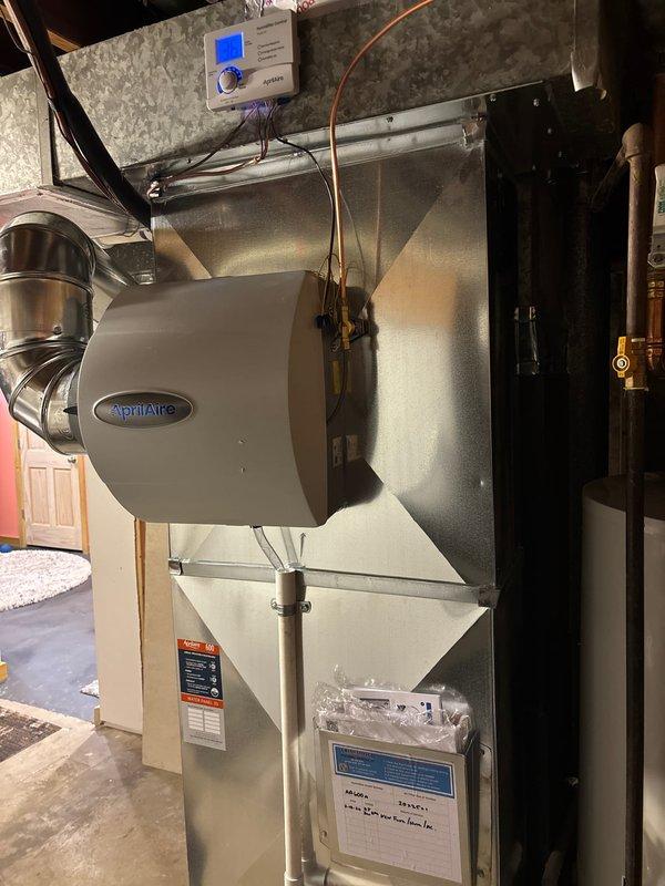 Successfully installed new furnace system with AprilAire humidifier and digital control panel in utility area, complete with proper ductwork connections and manufacturer documentation. Exterior Amana air conditioning unit was positioned on concrete pad with all necessary connections made to complete full HVAC system replacement.
