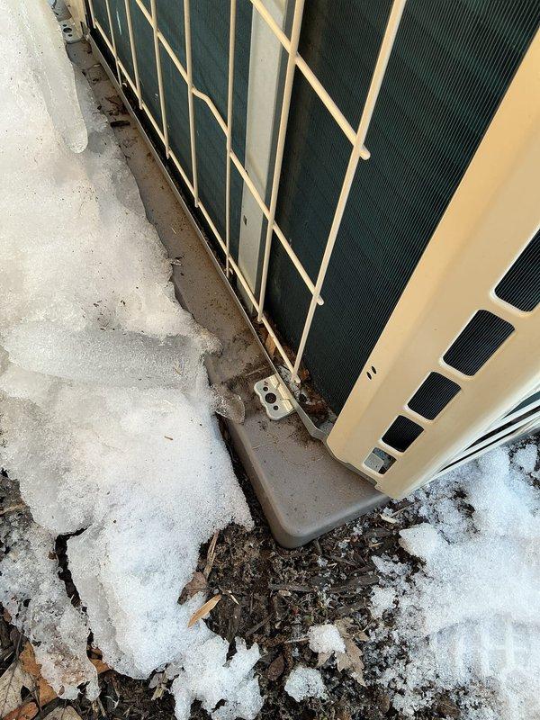 Inspected 6-month-old EnergiAir WT 03-2035 unit reportedly damaged by falling ice. Found visible corrosion at mounting bracket and unit base, with significant snow and ice accumulation against the condenser. Confirmed heating function operational; cooling function could not be tested due to winter conditions.