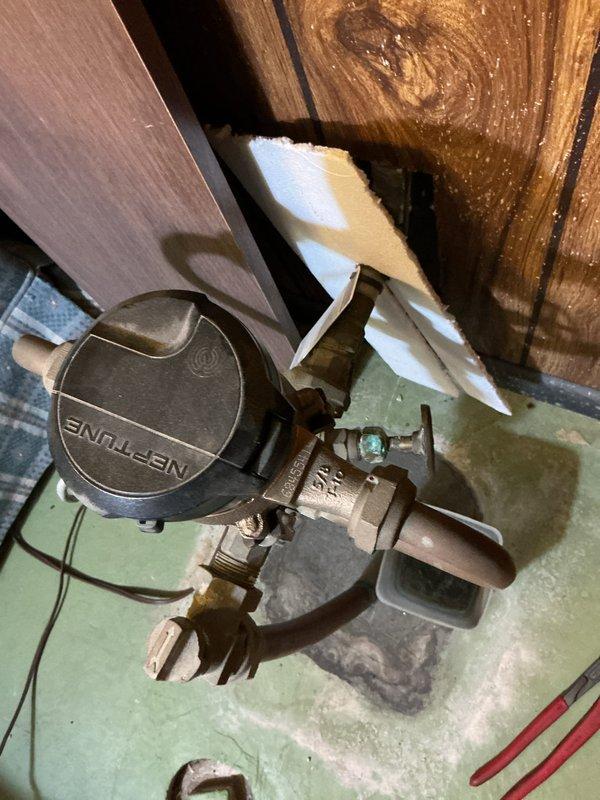 Responded to a plumbing leak call regarding a Neptune valve installation. Inspected the valve assembly mounted against wooden wall paneling with insulation material and identified the source of leakage affecting the kitchen sink area. Replaced faulty valve components and performed pressure testing to confirm proper function and verify leak resolution.