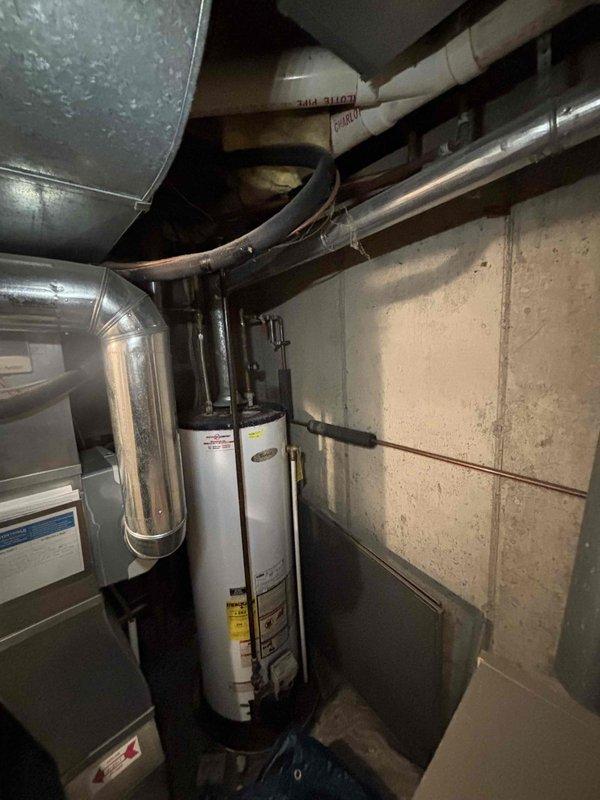 Completed annual heating maintenance service on a Whirlpool water heater (approximately 6 years old) with Energy Star rating WT 10-2029. System appears to be functioning properly with no humidity issues observed. Photographed the complete installation including water heater, associated ductwork, and plumbing connections for documentation purposes.