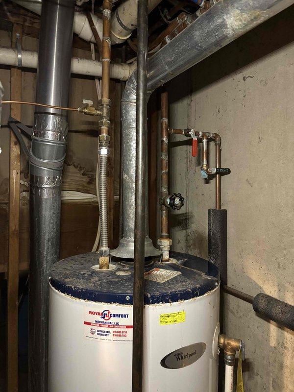 Completed annual heating maintenance service on a Whirlpool water heater (approximately 6 years old) with Energy Star rating WT 10-2029. System appears to be functioning properly with no humidity issues observed. Photographed the complete installation including water heater, associated ductwork, and plumbing connections for documentation purposes.