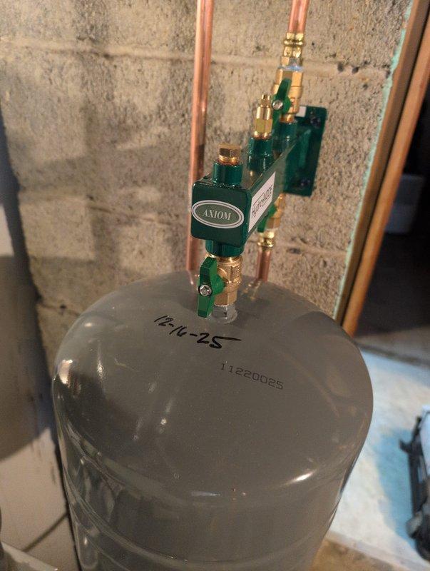 Successfully installed new boiler system in garage with complete copper pipe configuration. System includes Axiom control valve, expansion tank (serial #11220065), and all necessary supply/return lines. All components properly connected and system functioning as designed.