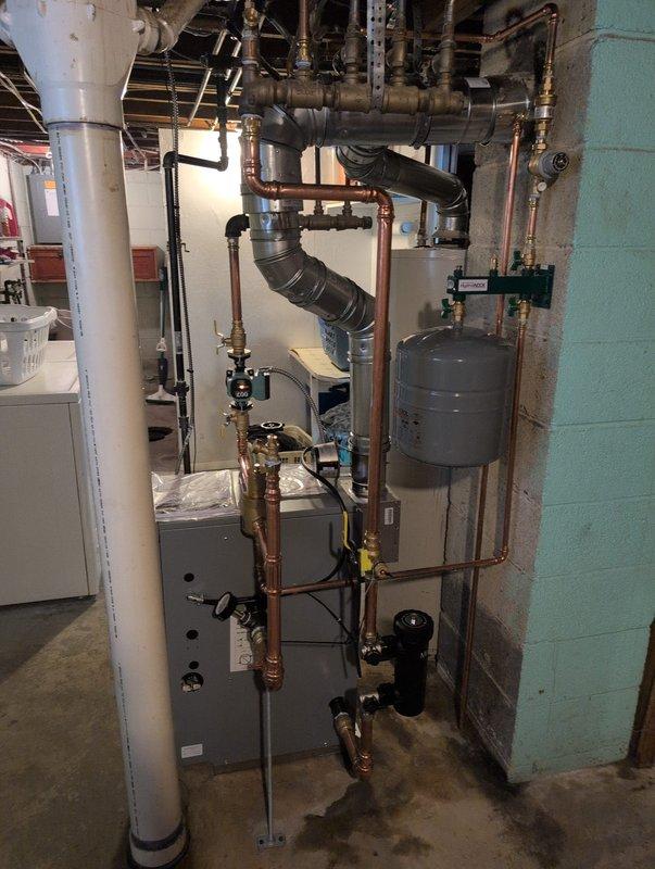 Successfully installed new boiler system in garage with complete copper pipe configuration. System includes Axiom control valve, expansion tank (serial #11220065), and all necessary supply/return lines. All components properly connected and system functioning as designed.
