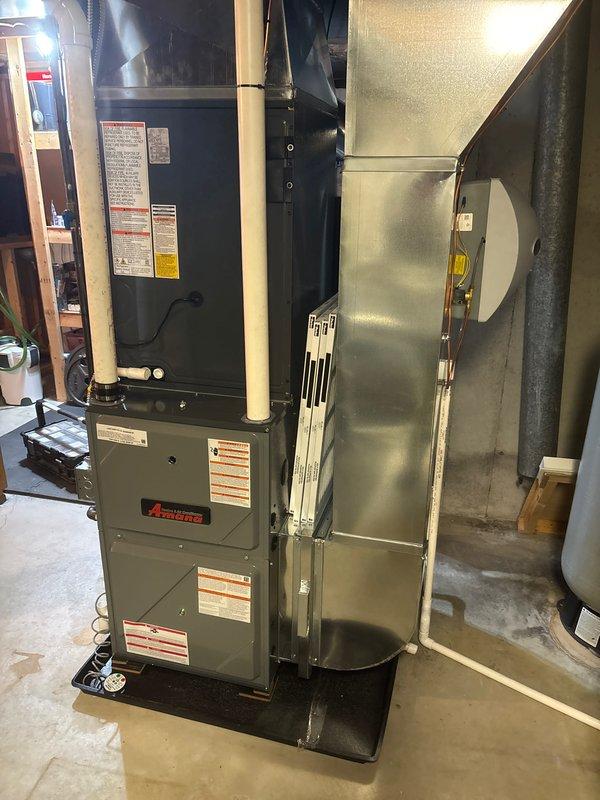 Completed installation of new Amana furnace and AC system in basement utility area. System includes properly installed PVC intake/exhaust venting, sheet metal ductwork connections, and all required safety components. Furnace was mounted on platform with proper clearances maintained for efficient operation.