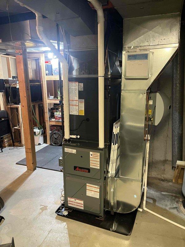 Completed installation of new Amana furnace and AC system in basement utility area. System includes properly installed PVC intake/exhaust venting, sheet metal ductwork connections, and all required safety components. Furnace was mounted on platform with proper clearances maintained for efficient operation.