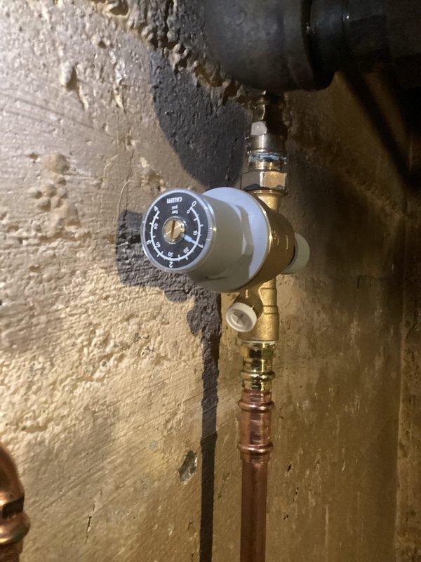 Installed new pressure regulator and mixing valve assembly on customer's boiler system. Connected copper supply lines to the brass valve components and verified proper pressure readings on the gauge. System now operating within normal parameters with no leaks observed at any connection points.