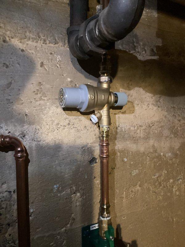 Installed new pressure regulator and mixing valve assembly on customer's boiler system. Connected copper supply lines to the brass valve components and verified proper pressure readings on the gauge. System now operating within normal parameters with no leaks observed at any connection points.