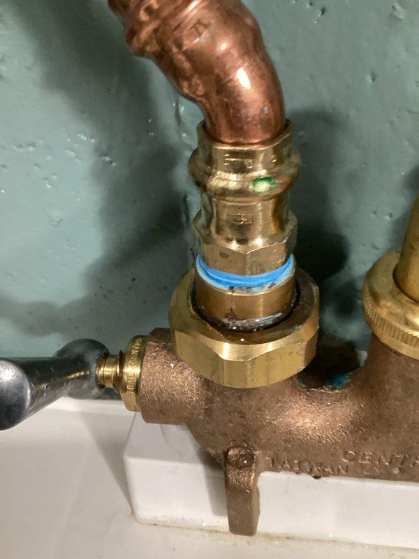 Repaired plumbing leak at a brass Central mixing valve in 47-year-old residence. Identified compromised compression fitting with blue indicator ring at copper pipe connection. Replaced fitting and tested system to confirm complete resolution of leak that had been occurring for approximately ten days.
