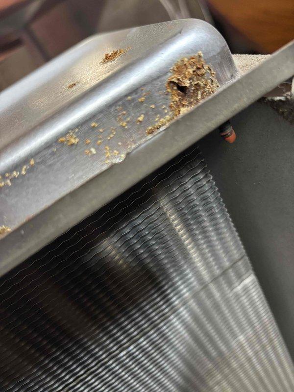 Replaced heavily corroded heat exchanger (HTX) unit that exhibited significant rust damage along the metal housing and seams. Documented pre-replacement condition with photos showing extensive oxidation on the metal frame while the internal coil structure remained functional.