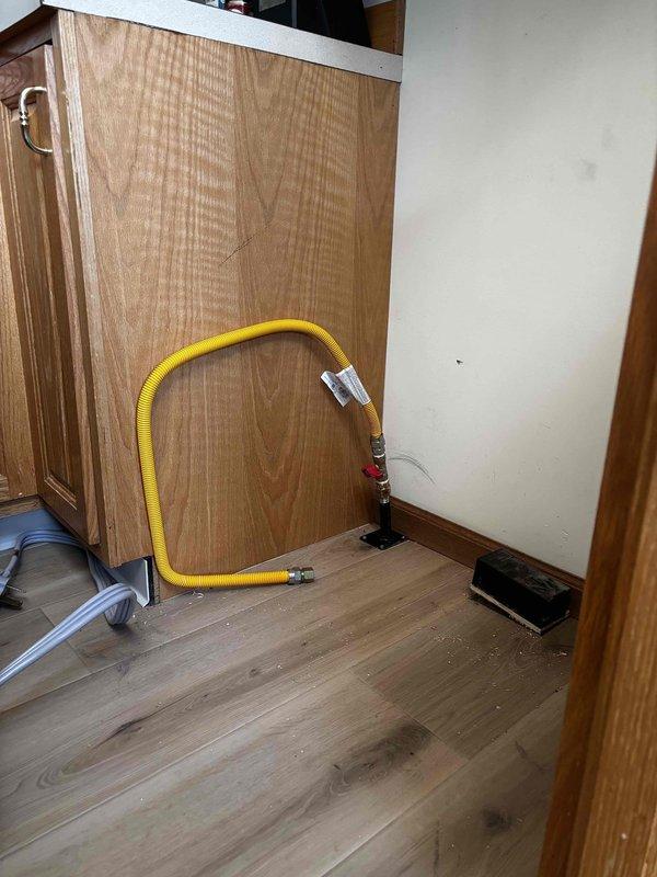Completed installation of a new gas line for customer's stove, including a new shut-off valve and appliance connector. Work involved routing yellow flexible gas line with appropriate fittings and installing a red shut-off valve where the line connects to the wall fixture. Accessed ceiling joists to properly connect to existing gas supply infrastructure, ensuring secure connections and proper installation according to code requirements.