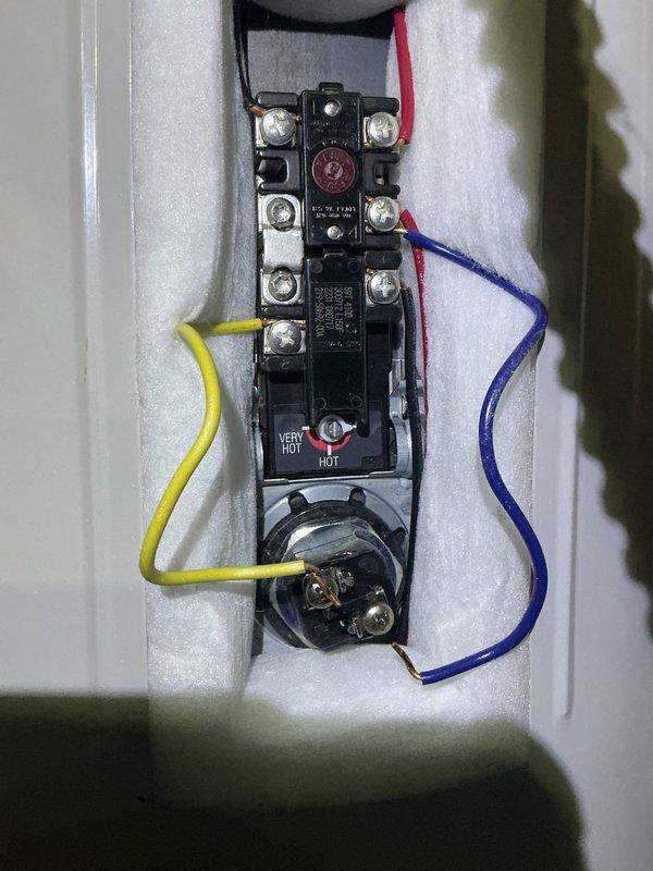 Diagnosed electric water heater with significant corrosion and burn marks at the upper electrical connection compartment. Inspection revealed water leakage into the thermostat area causing electrical damage and terminal deterioration. Replaced damaged thermostat assembly and cleaned corrosion to restore proper operation.