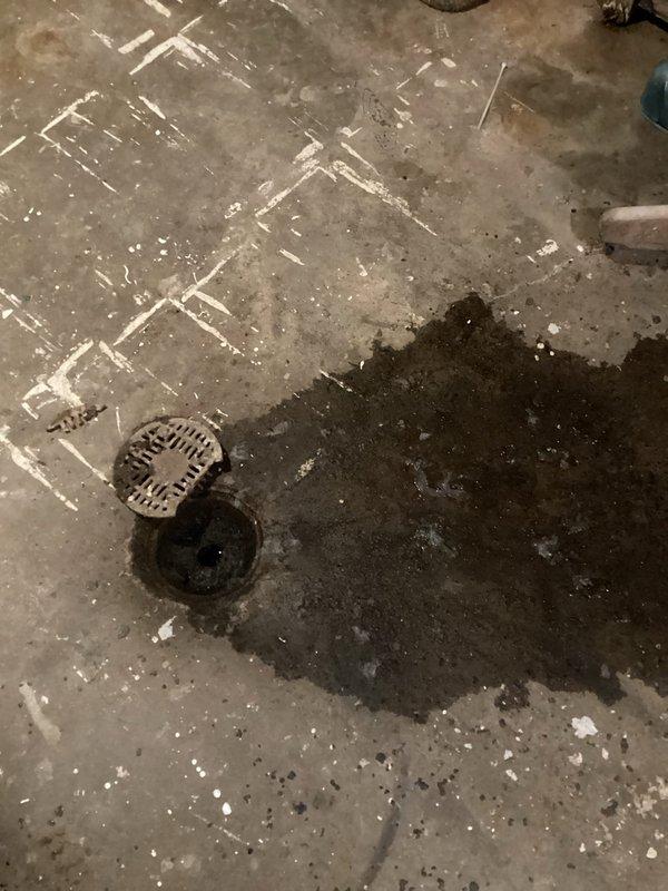 Responded to basement flooding complaint occurring during heavy rain and household water usage. Inspected concrete floor drain system, finding significant water poolback and pooling around main floor drain. Performed drain augering service with snake to clear blockage in century-old drainage pipes, successfully restoring proper water flow and eliminating basement flooding issue.