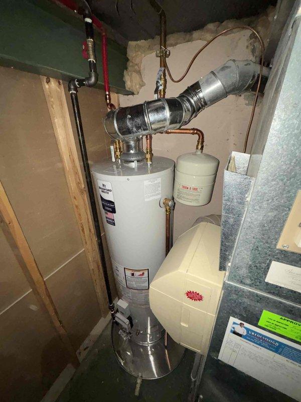 Successfully installed a 40-gallon Bradford White automatic storage water heater with natural gas connection. Completed all necessary piping connections including copper lines with brass fittings and proper ductwork integration. Installation included mounting of expansion tank and ensuring all clearances and pressure specifications were met according to manufacturer requirements.