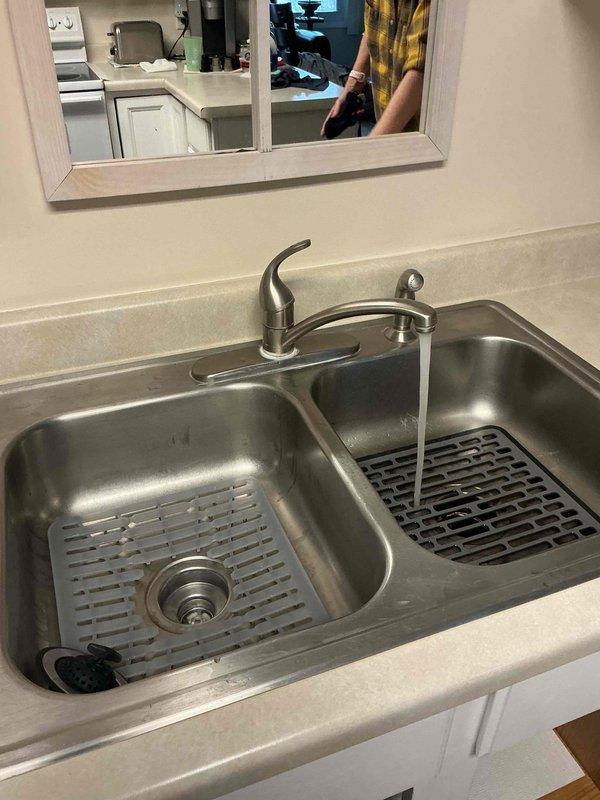 Responded to service call for kitchen faucet with minor drip leak. Diagnosed and replaced faulty kitchen faucet with new brushed nickel single-handle model. Tested installation with water flow to both basins of stainless steel double sink, confirming proper function and no leaks present.