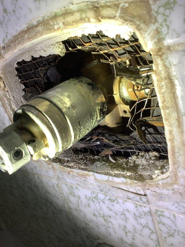 Inspected piping system through wall access point and discovered significant corrosion and mineral buildup on brass fittings and metal pipes. Observed evidence of moisture damage and possible mold growth around the opening, indicating an active leak. Replaced deteriorated components and sealed the access point to prevent further water intrusion.