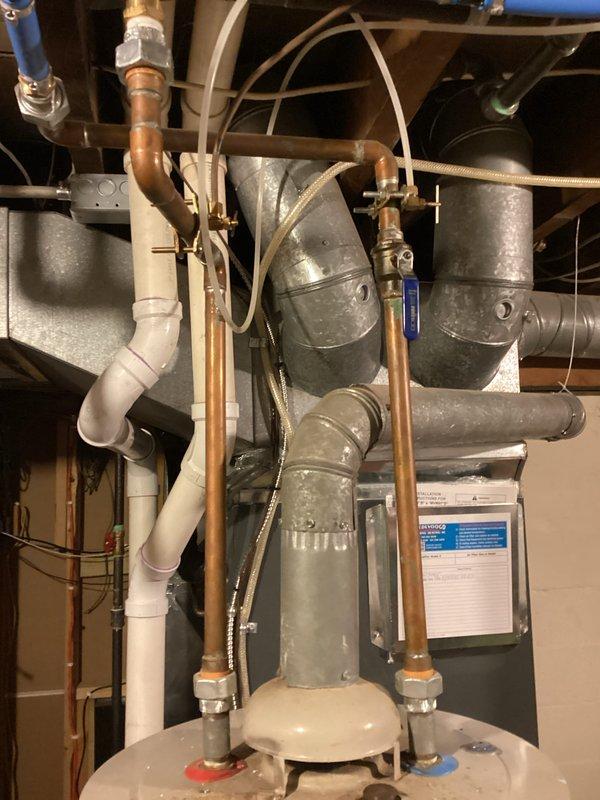 Completed water heater replacement estimate for aging unit (2024 model). Documented existing installation configuration including copper water lines with proper hot/cold connections and surrounding HVAC ductwork. Photographed current mechanical system setup for reference in preparation of replacement proposal.