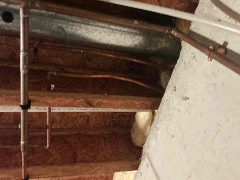 Responded to emergency plumbing leak in basement requiring water shutoff to property. Upon inspection, discovered copper pipe leak in crawlspace/attic area where pipes run alongside HVAC ductwork and structural framing. Successfully isolated and repaired the compromised section of copper piping, restored water service, and verified system integrity with pressure testing.