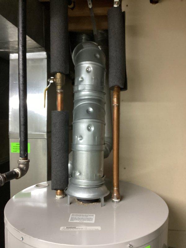Responded to service call for 7-year-old leaking water heater. Visual inspection confirmed water leakage from tank. Diagnosed as tank failure requiring replacement; documented condition with photos showing the existing water heater installation including vent assembly, supply lines, and connection points.