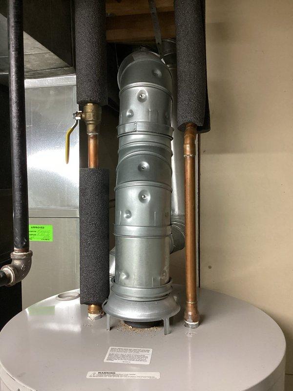 Responded to service call for 7-year-old leaking water heater. Visual inspection confirmed water leakage from tank. Diagnosed as tank failure requiring replacement; documented condition with photos showing the existing water heater installation including vent assembly, supply lines, and connection points.