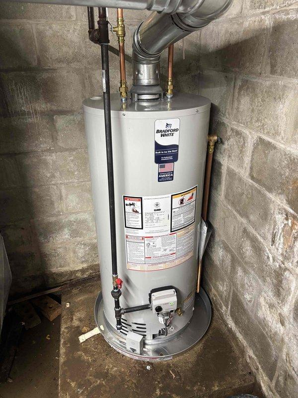 Successfully installed a new Bradford White water heater in the basement utility area, including all necessary copper pipe connections and metal vent piping. Unit was properly secured against the concrete block wall with all manufacturer specifications followed for safe operation.