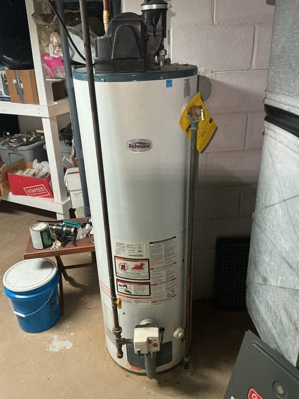 Performed annual heating maintenance on 15-year-old GDM furnace. Observed significant copper pipe corrosion at water heater connection point with mineral buildup spreading onto concrete floor. Documented Richmond water heater condition with visible warning tags and connection issues for future reference.