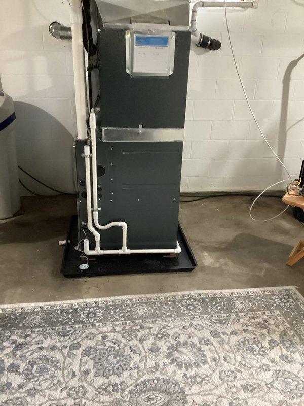 Completed installation of new warranty furnace in basement utility area. Unit was properly mounted on drain pan with all necessary PVC pipe connections and ductwork secured to existing system. Digital control panel was verified operational with system functioning as designed.