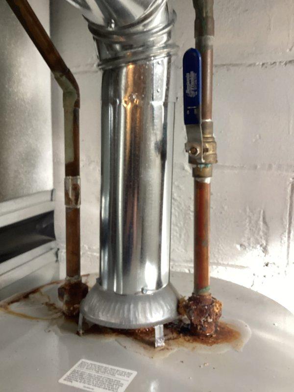 Conducted water heater estimate in basement utility room where existing unit shows significant corrosion and rust on copper supply pipes and connection points. Documented current installation configuration including ventilation system, shutoff valves, and surrounding utility infrastructure for replacement recommendation.