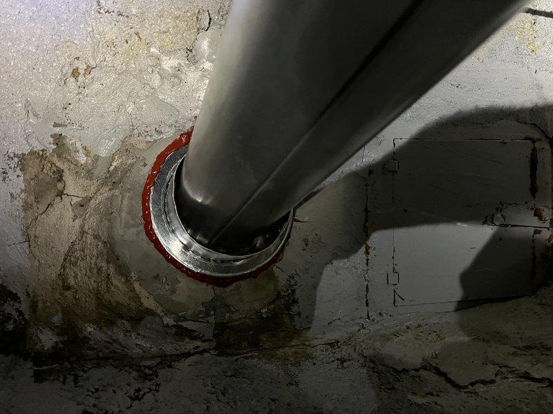 Successfully installed a chimney liner system through a challenging access point. The installation required navigating through a narrow passageway with moisture concerns, and properly sealed the metal liner where it penetrates the concrete wall using appropriate fire stop collars.
