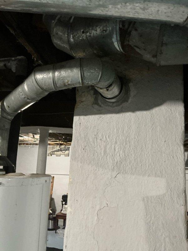 Performed diagnostic assessment on 11-year-old Concord central AC unit which is non-operational and requires replacement. Documented existing system configuration including forced air furnace with ductwork throughout residence. Photographed outdoor condensing unit showing significant wear and deteriorated components, as well as the indoor equipment connections and existing ductwork in utility space.